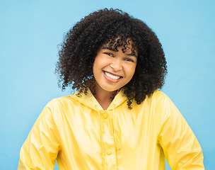 Image showing Woman, smile and happy in portrait with fashion for winter, rain coat and beauty isolated on blue background. .African person, happiness in studio and style with jacket, mockup and trendy headshot