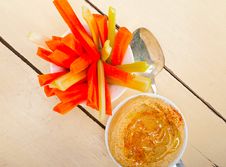 Image showing fresh hummus dip with raw carrot and celery