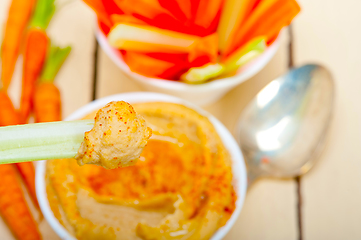 Image showing fresh hummus dip with raw carrot and celery