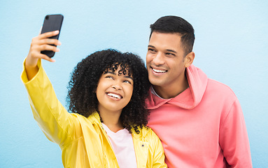 Image showing Friends, phone and face with smile for selfie on a blue background for fashion, style or friendship together. Young man and woman smiling in happiness looking at smartphone for happy photo moments