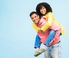 Image showing Happy couple, bonding or piggyback portrait on isolated blue background in city travel, date or fun game. Smile, happy man or carrying black woman in silly, goofy or playful trust, support or love