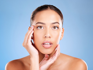 Image showing Face portrait, skincare and beauty of woman in studio on a blue background. Hands, natural cosmetics and makeup of young female model with healthy, smooth and glowing skin after facial treatment.