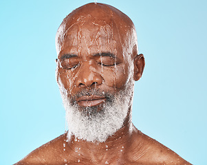 Image showing Shower, black man and water for cleaning, skincare and wellness on blue studio background. Mature male, elderly guy and face wet for hygiene, washing or body care for beauty, cosmetics or clear skin