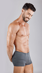 Image showing Fitness, body and man in underwear in a studio for health, wellness and exercise for muscle. Happy, smile and muscular male model from Puerto Rico isolated by a gray background after a workout.