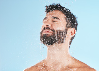 Image showing Man shower, cleaning face and studio for self care wellness, relax and beauty by blue background. Model, skincare and water drop on facial, beard and self love for health, body or clean by backdrop