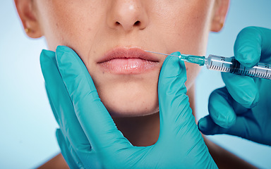 Image showing Botox, hands and mouth surgery with a woman and doctor in studio on a blue background for face change. Beauty, skin and injection with a surgeon holding a syringe for female client facial filler