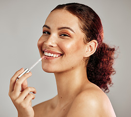 Image showing Woman, smile portrait and apply lipstick for beauty, cosmetics dermatology and skincare wellness in grey background. Female model, face and makeup application or lip balm product for happy self care