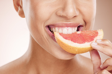 Image showing Diet, nutrition and woman eating grapefruit for skincare, beauty glow and vegan detox on a studio background. Vitamin c, health and mouth of a model advertising a fruit for care of body and skin