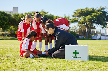 Image showing Sports, first aid and children soccer team with an injury after a game in a huddle helping a girl athlete. Fitness, training and kid with a sore, pain or muscle sprain on an outdoor football field.