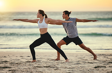 Image showing Couple, warrior pose and beach yoga at sunset for health, fitness and wellness. Exercise, zen chakra and man and woman stretching, training and practicing pilates for balance outdoors at seashore.