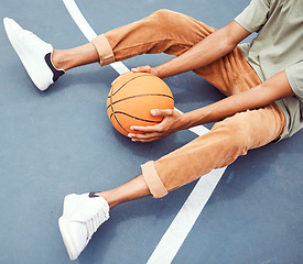 Image showing Basketball, hands and fitness with a sports man sitting alone on a court, holding a ball from above. Basketball court, break and exercise with a male basketball player or athlete resting at practice