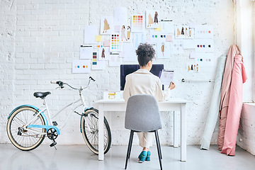 Image showing Designer woman, workshop and desk by wall, moodboard and reading documents with sketch, planning or idea. Startup fashion expert, studio and sitting at table for small business growth, vision or goal