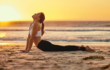 Image showing Yoga, cobra stretch and woman at beach for fitness, health and wellness. Sunset, zen chakra and female yogi practicing pilates, meditation and training, stretching and exercise outdoors at seashore.