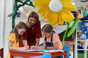 Image showing Creative kids during an art class in a daycare center or elementary school classroom drawing with female teacher.