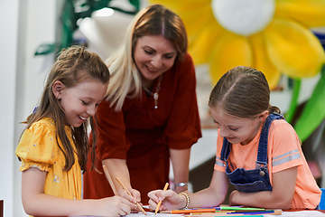 Image showing Creative kids during an art class in a daycare center or elementary school classroom drawing with female teacher.