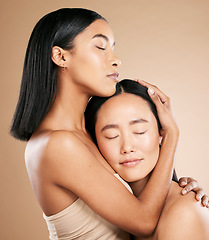 Image showing Beauty, love and diversity with a model woman friends in studio on a beige background for natural skincare. Spa, health and wellness with an attractive young female holding the head of her friend