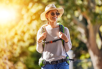 Image showing Nature, adventure and woman hiking in a forest for outdoor exercise, wellness and fresh air. Happy, smile and female trekking or walking in a green garden with a backpack and sunglasses in Canada.