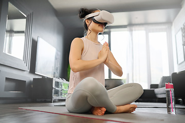 Image showing VR, meditation and fitness with a woman using a headset to access the metaverse in her home for health. Virtual reality, yoga and exercise with a young female yogi meditating in her house using 3d ai