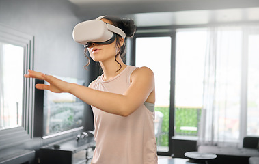 Image showing Virtual reality, metaverse and technology with a woman in the living room of her home using a headset to access a 3d game. Futuristic, VR and gaming with a female gamer using ai to play games