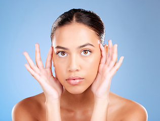 Image showing Face portrait, skincare and beauty of woman in studio on a blue background. Hands, natural cosmetics and makeup of young female model with healthy, smooth and glowing skin after facial treatment.