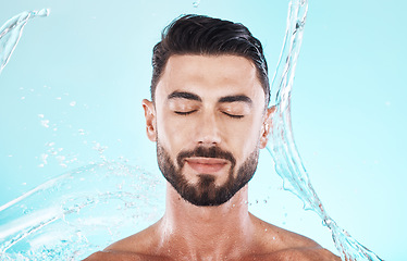 Image showing Water, splash and skincare with face of man for shower, self care and natural cosmetics. Luxury, hydration and refreshing with model for dermatology, wellness and cleaning in blue background studio