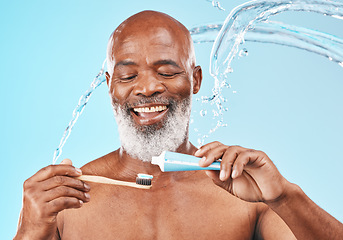 Image showing Water, splash and man with dental care in a studio for mouth health and wellness. Toothpaste, toothbrush and elderly African guy brushing his teeth for fresh oral hygiene isolated by blue background.