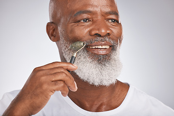 Image showing Black man, facial roller and skincare to massage skin for self care with dermatology beauty tool. Headshot of a happy senior male with a stone on grey studio background for spa treatment for the face