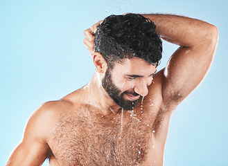 Image showing Water, shower and a man washing hair with shampoo in studio on a blue background for beauty or hygiene. Hair, cleaning or treatment with a handsome male wet in the bathroom while bathing for haircare