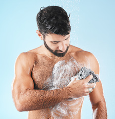 Image showing Washing body, skincare and man cleaning for hygiene, natural health and shower on a blue studio background. Morning routine, soap and healthy model showering to clean skin with a cloth and water