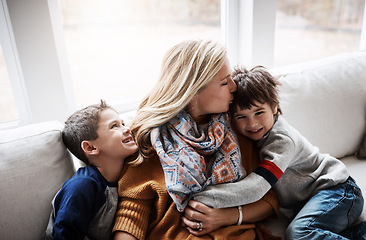 Image showing Happy family, hug and kiss from mother to children while together on living room sofa at the house. Woman and kids in lounge for love, care and safety while bonding to relax and spend time at. home