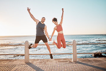 Image showing Fitness, jump and portrait of a couple at beach for training fun, support and celebration of goal. Energy, happy and excited man and woman jumping while holding hands at the sea for cardio in Spain
