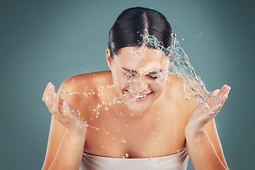 Image showing Skincare, face and water splash on woman cleaning skin for hygiene and hydration isolated in a studio background. Self care, dermatology and young female washing or grooming for adult beauty