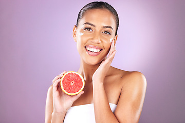 Image showing Woman, face skincare or grapefruit product on purple studio background for organic dermatology, healthcare wellness or self care grooming. Portrait, smile or happy beauty model and fruit facial cream