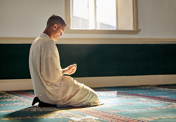 Image showing Mosque, worship and muslim man in prayer on his knees for gratitude, support or ramadan for spiritual wellness. Religion, tradition and islamic guy praying or reciting quran to allah at islam temple.