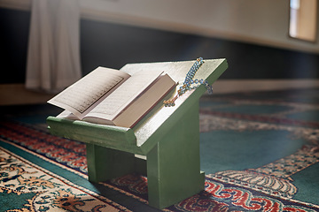 Image showing Quran, prayer beads and mosque with an open book and a rosary in an empty holy room or temple ready for praying. Islamic misbaha, tasbih or sibha and scripture in a muslim place of worship for eid