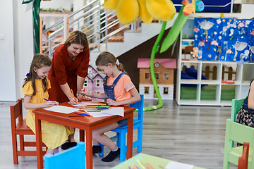 Image showing Creative kids during an art class in a daycare center or elementary school classroom drawing with female teacher.