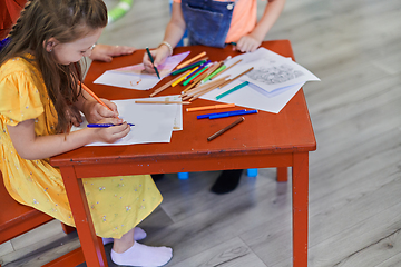 Image showing Close up photo of kids during an art class in a daycare center or elementary school classroom drawing with female teacher.