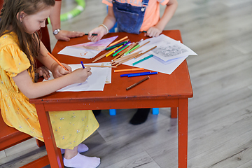 Image showing Creative kids during an art class in a daycare center or elementary school classroom drawing with female teacher.