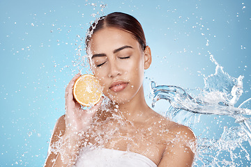 Image showing Water splash, orange and natural skincare wellness in blue studio background for organic facial care cleaning, dermatology detox and fruit nutrition. Model face, citrus vitamin c and cosmetics clean