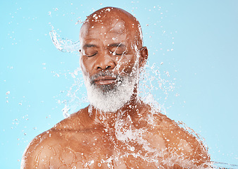 Image showing Senior black man, water splash and skincare in studio for wellness, clean or health facial by backdrop. Man, model face and water on skin, healthy self care or anti-aging beauty by blue background
