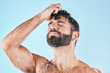 Image showing Water, shower and a man washing hair with shampoo in studio on a blue background for beauty or hygiene. Hair, cleaning and bathroom with a handsome male wet in the bathroom while bathing for haircare