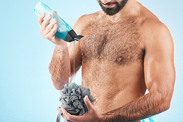 Image showing Shower gel, body care and man in a studio for skin hygiene, health and wellness after a shower. Soap, morning routine and male model cleaning or washing his wet body with a sponge by blue background.