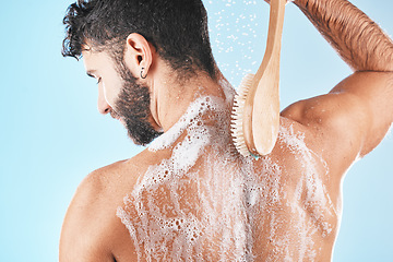 Image showing Back, man and shower with foam, skincare and cleaning for body care, wellness and against blue studio background. Male, guy and washing with water, beauty and cosmetics for grooming, bare and fresh