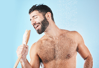 Image showing Shower, singing and cleaning with a man model in studio on a blue background using a loofah to sing. Water, bathroom and hygiene with a handsome male wet while washing for personal body care