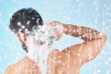 Image showing Shower, water and man with soap for cleaning, washing and hygiene on blue background in studio. Grooming, bathroom and back of male with foam, sponge and water splash for skincare, wellness and spa