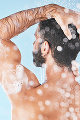 Image showing Shower, water and man cleaning hair with shampoo, conditioner and hair products on blue background. Hygiene, grooming and back of male washing body in bathroom for self care, wellness and skincare