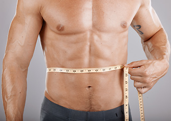 Image showing Man, body and tape measure on abdomen in studio on gray background. Health, fitness and male model with measuring tape for abs to track exercise training results, muscle goals or weight loss target.