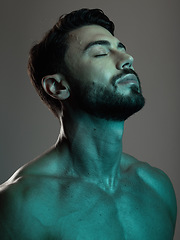 Image showing Man, face and neon with beauty and skincare, grooming and wellness with eyes closed against studio background. Healthy skin, relax in blue light and peace, self care and cosmetic facial and treatment