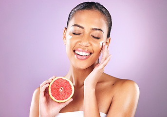 Image showing Woman, face skincare or grapefruit cream on purple studio background in organic dermatology, healthcare sunscreen wellness or self care grooming. Smile, happy or beauty model and fruit facial product