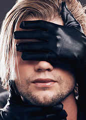 Image showing Fashion, beauty and model with leather gloves on his face in a studio with edgy, punk and trendy style. Non binary, LGBTQ and closeup of a man with a luxury, fancy or stylish dark aesthetic.